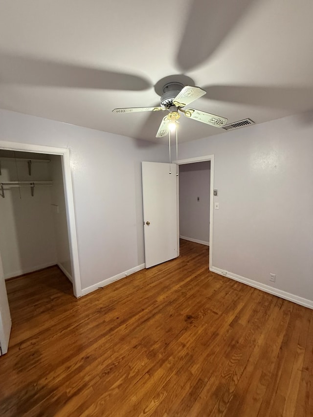 unfurnished bedroom featuring ceiling fan, a closet, and hardwood / wood-style flooring