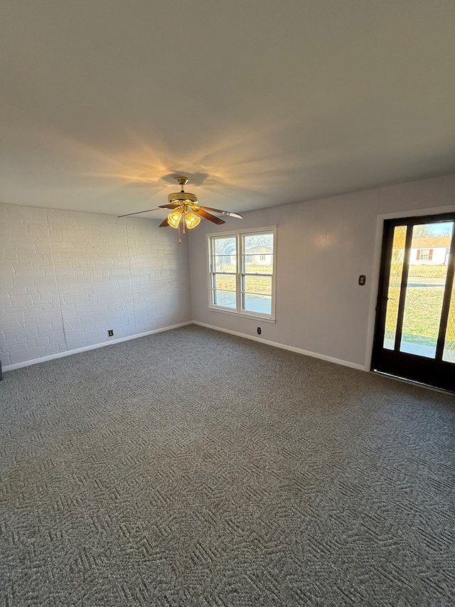 empty room with ceiling fan, carpet floors, and brick wall