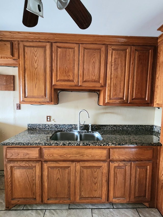 kitchen featuring dark stone countertops, sink, and light tile patterned flooring