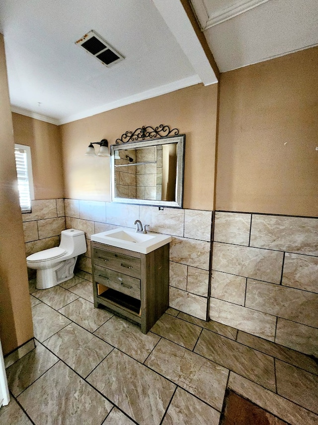 bathroom with vanity, toilet, tile walls, and crown molding