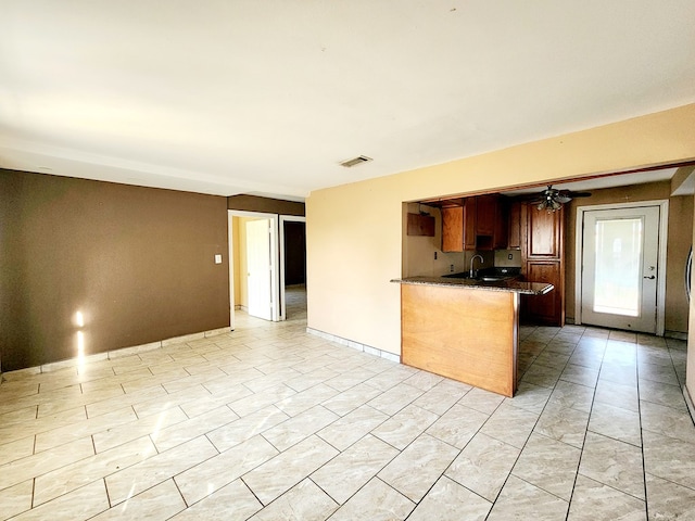 kitchen featuring kitchen peninsula, ceiling fan, and sink