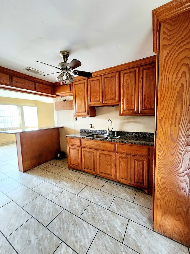 kitchen with ceiling fan, sink, and dark stone counters