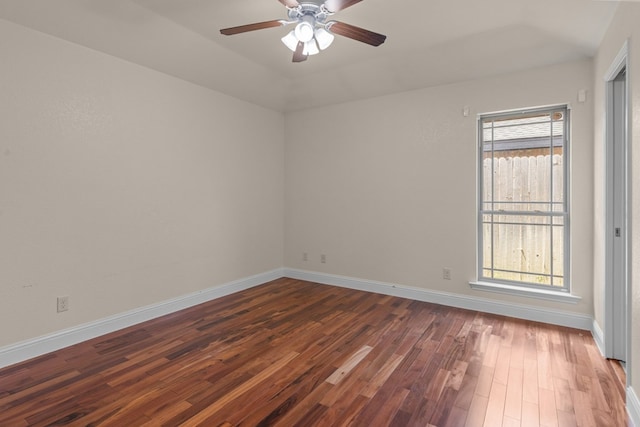 empty room featuring wood finished floors, ceiling fan, baseboards, and lofted ceiling