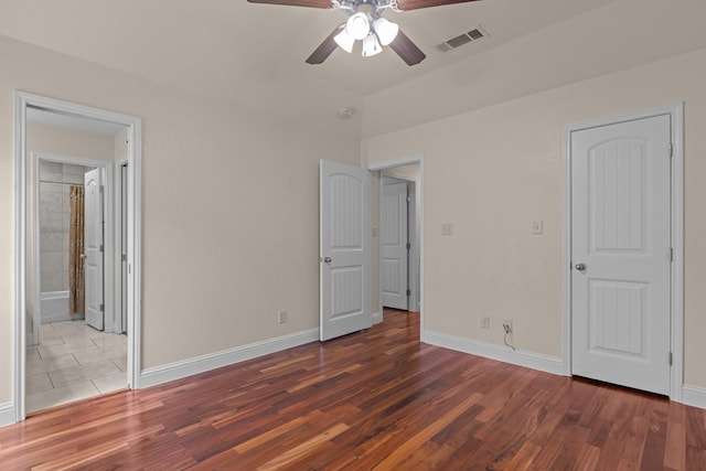 unfurnished bedroom featuring wood finished floors, a ceiling fan, ensuite bathroom, and baseboards