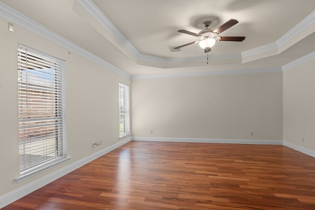 unfurnished room featuring a raised ceiling, wood finished floors, ceiling fan, crown molding, and baseboards