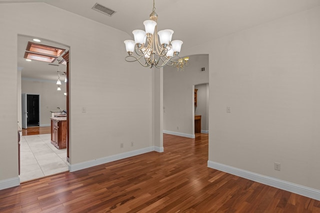 unfurnished room featuring light wood-style floors, a chandelier, and baseboards