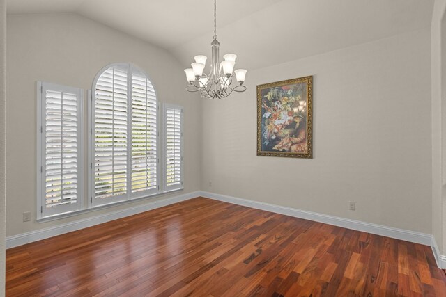 unfurnished room with lofted ceiling, a chandelier, wood finished floors, and baseboards