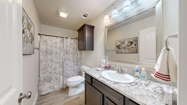 full bath featuring vanity, a shower with shower curtain, wood finished floors, visible vents, and toilet