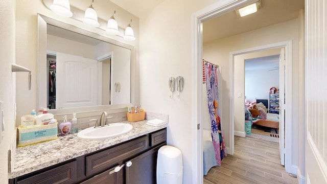 bathroom with vanity, a shower with shower curtain, baseboards, and wood tiled floor