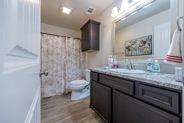 bathroom featuring visible vents, toilet, vanity, and wood tiled floor