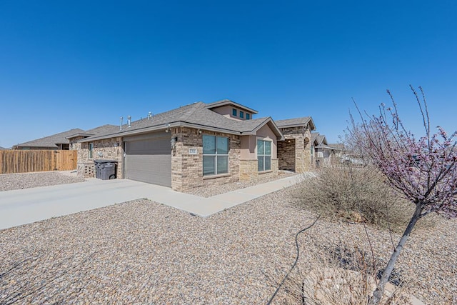 view of front of home featuring fence, stucco siding, a garage, stone siding, and driveway