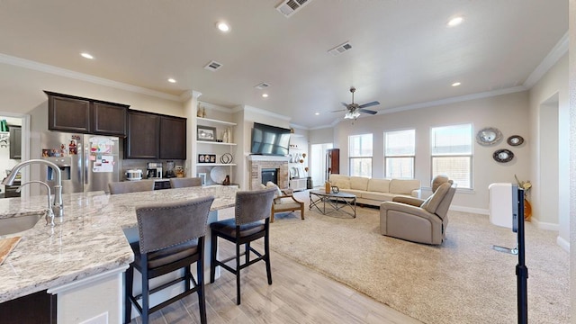 kitchen featuring a sink, visible vents, dark brown cabinets, and stainless steel fridge with ice dispenser