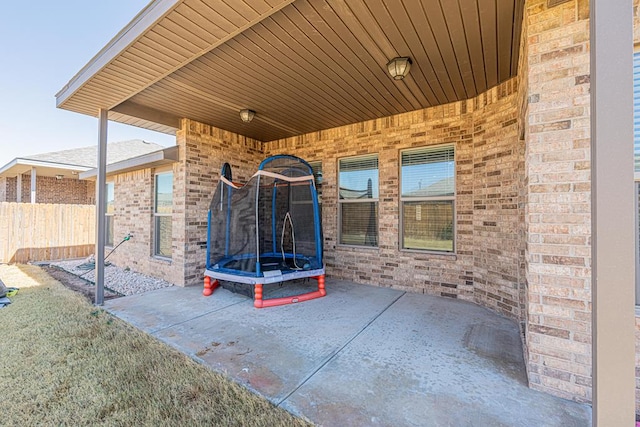 view of patio with a trampoline and fence