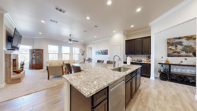 kitchen with visible vents, a fireplace with raised hearth, dishwasher, and a sink