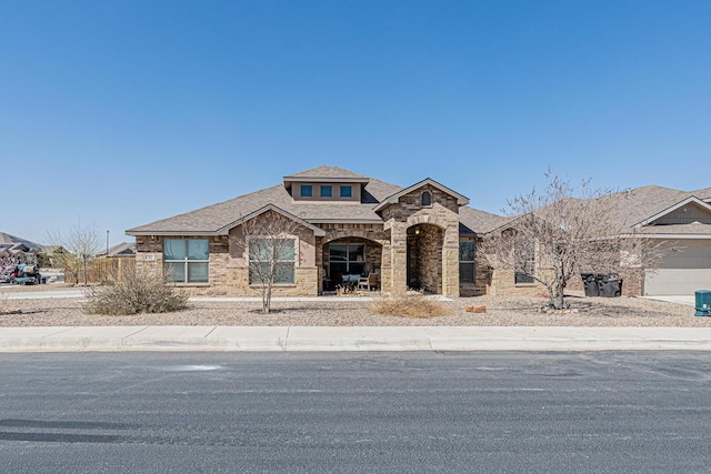 view of front of property featuring stone siding and a shingled roof