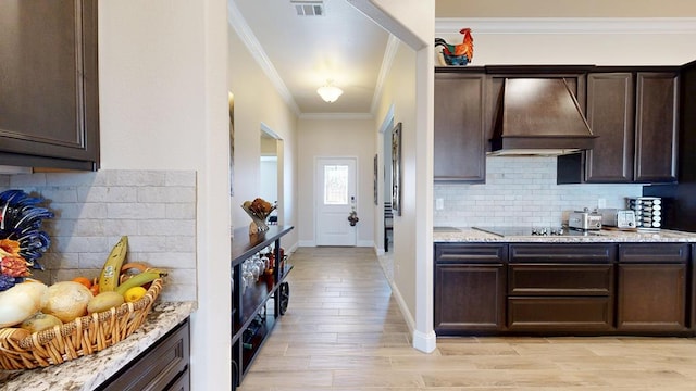 kitchen featuring visible vents, dark brown cabinets, crown molding, black electric stovetop, and custom exhaust hood