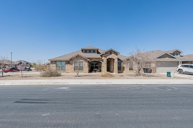 view of front of property featuring a garage, stone siding, and concrete driveway