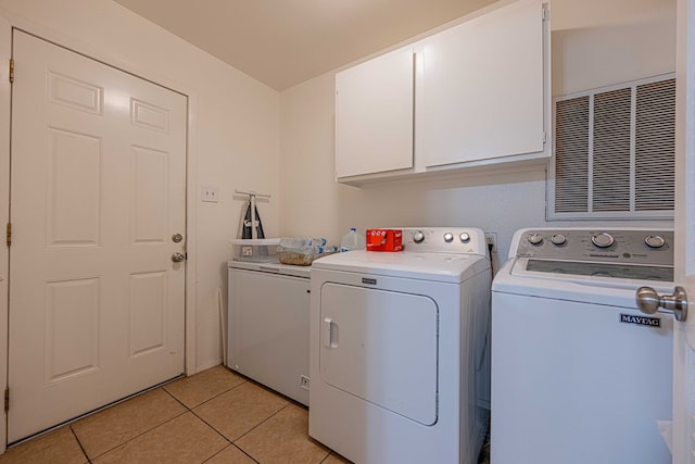 clothes washing area with light tile patterned flooring, cabinets, and independent washer and dryer