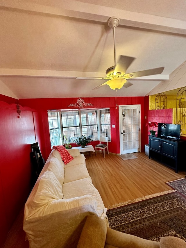 living room featuring lofted ceiling with beams, wood walls, a ceiling fan, and wood finished floors