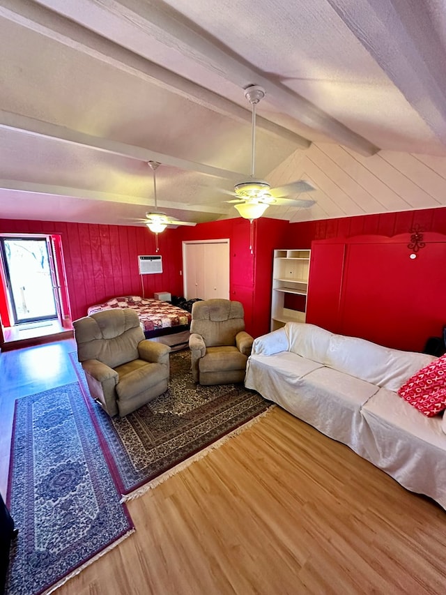 living room featuring vaulted ceiling with beams, a ceiling fan, wood walls, a textured ceiling, and wood finished floors