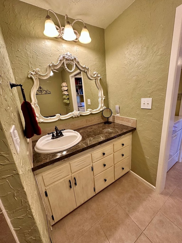 bathroom with tile patterned flooring, vanity, a textured ceiling, and a textured wall