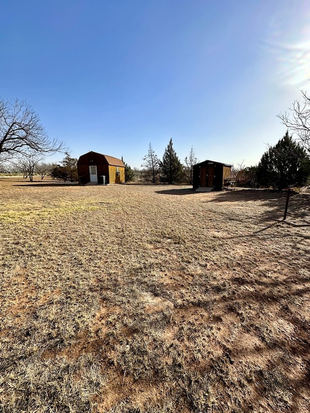 view of yard with a storage unit, a rural view, and an outdoor structure