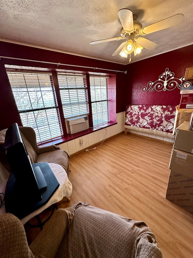 living area featuring light wood finished floors, ceiling fan, cooling unit, and a textured ceiling