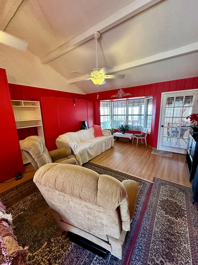 interior space with a ceiling fan, vaulted ceiling with beams, wooden walls, and wood finished floors