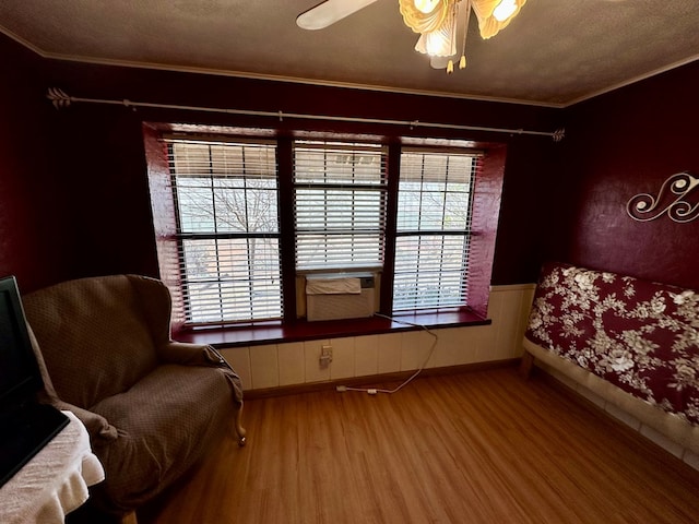 sitting room featuring ceiling fan, cooling unit, wood finished floors, and crown molding