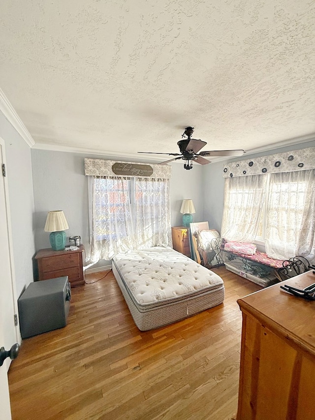 bedroom featuring crown molding, ceiling fan, hardwood / wood-style flooring, and a textured ceiling