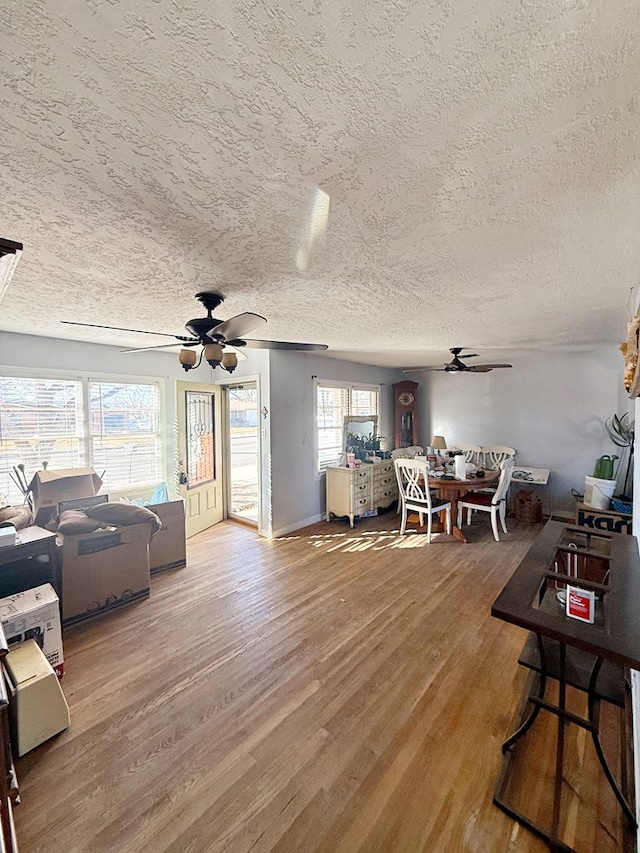 living room with ceiling fan, wood-type flooring, and a textured ceiling