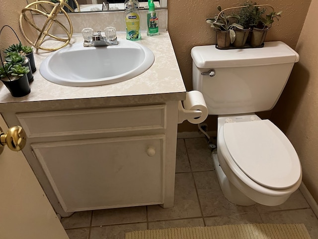 bathroom featuring tile patterned flooring, a textured wall, vanity, and toilet