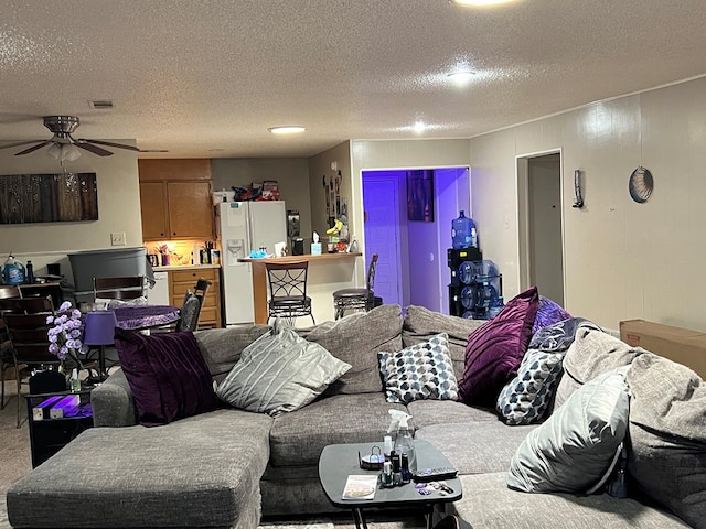 living room with ceiling fan, a textured ceiling, and visible vents