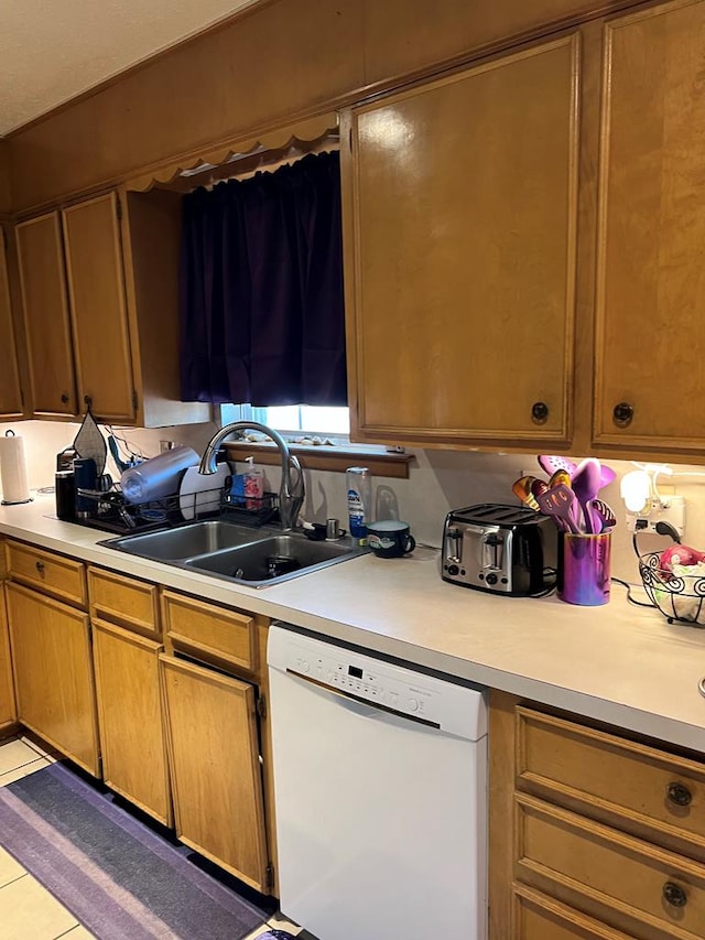 kitchen featuring light countertops, brown cabinetry, white dishwasher, and a sink