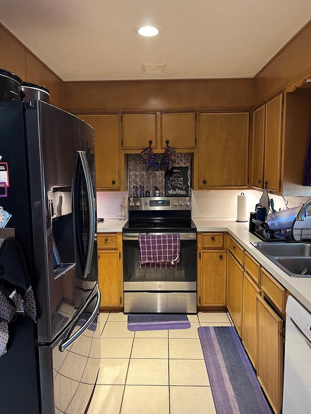 kitchen featuring dishwasher, stainless steel electric range oven, black refrigerator with ice dispenser, light countertops, and a sink