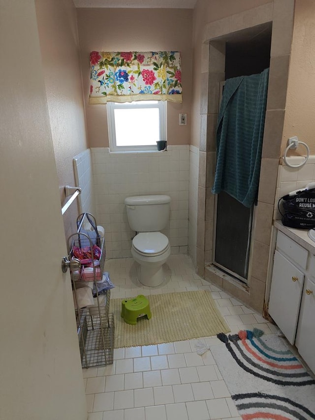 bathroom with a stall shower, tile patterned flooring, tile walls, and toilet