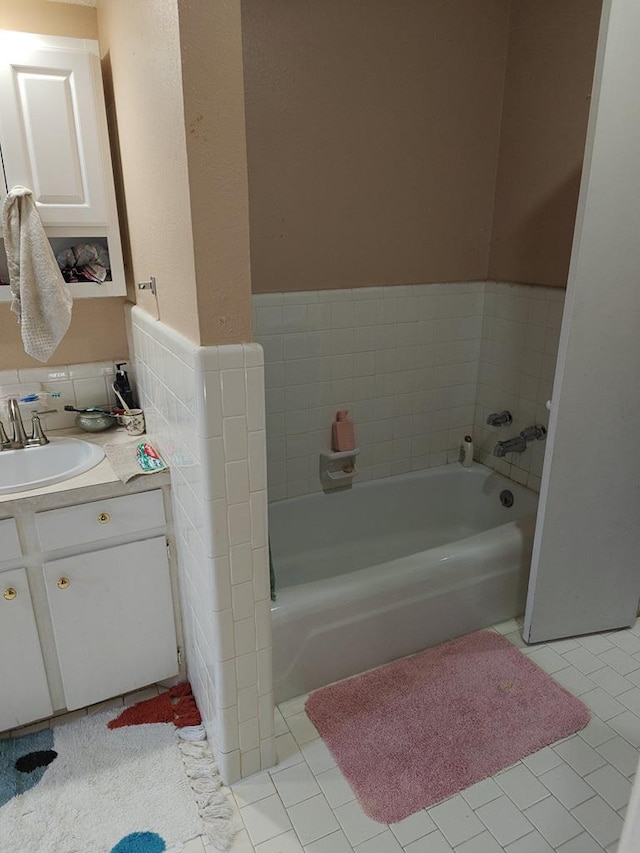 bathroom with tile patterned flooring, a garden tub, vanity, and tile walls