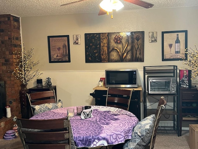 carpeted dining area with a brick fireplace, ceiling fan, and a textured ceiling