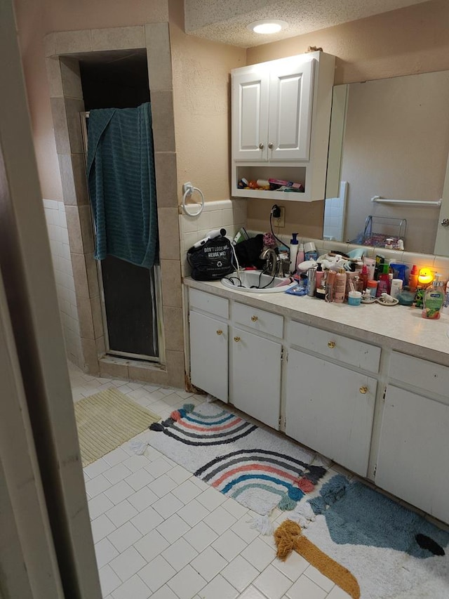 bathroom with a textured ceiling, a shower stall, vanity, and tile patterned floors