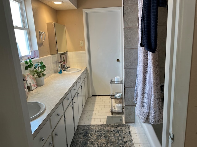 bathroom featuring double vanity, tile patterned flooring, a shower, and a sink