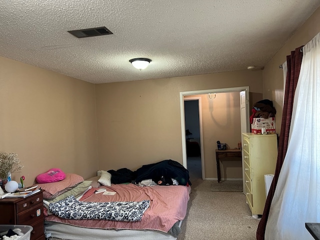 carpeted bedroom featuring visible vents and a textured ceiling