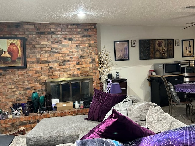 living room featuring a textured ceiling, a brick fireplace, and visible vents