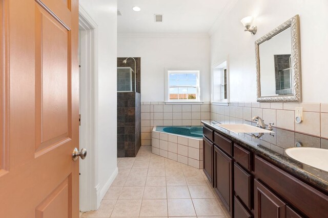 bathroom with tile patterned flooring, crown molding, shower with separate bathtub, vanity, and tile walls