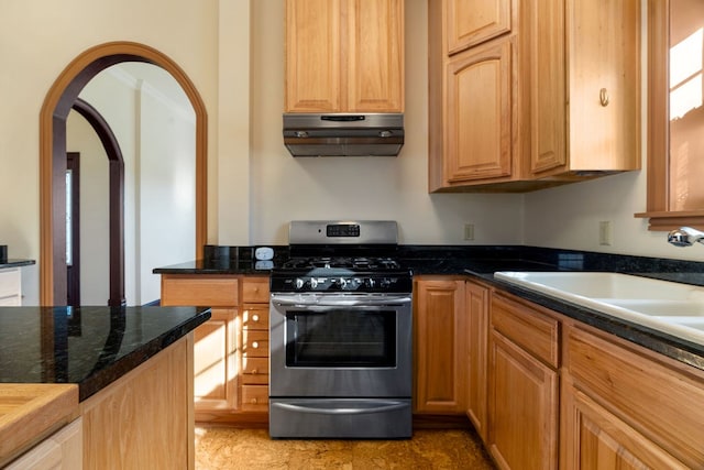 kitchen featuring stainless steel range with gas cooktop, sink, and dark stone counters