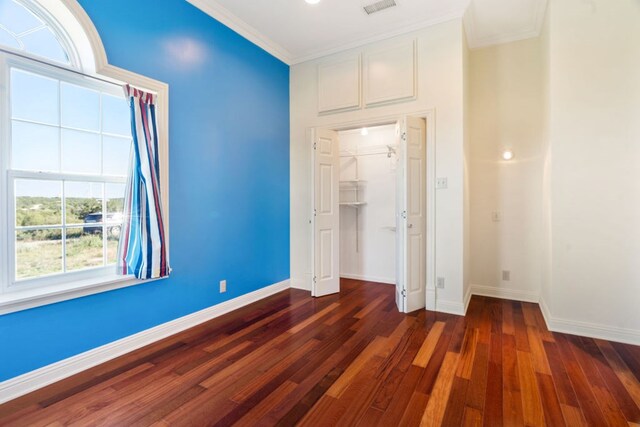 unfurnished bedroom featuring dark hardwood / wood-style floors, crown molding, and a closet