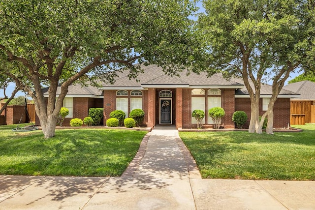 2201 Hereford Blvd, Midland, TX 79707 - view of front of home featuring fence, roof with shingles, brick siding, and a front yard