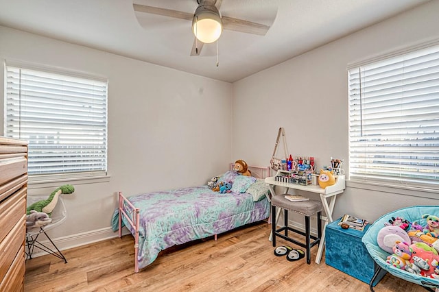 bedroom featuring ceiling fan, light wood-type flooring, and multiple windows