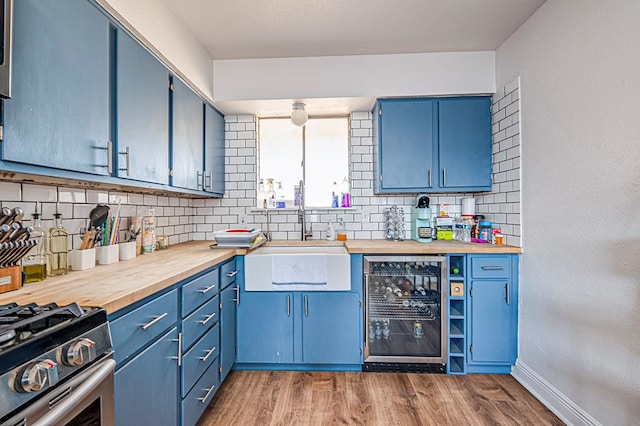 kitchen featuring decorative backsplash, sink, blue cabinetry, and beverage cooler