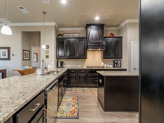 1906 Overshine Ln, Midland, TX 79705 - kitchen featuring custom range hood, a sink, stainless steel dishwasher, ornamental molding, and light wood-type flooring