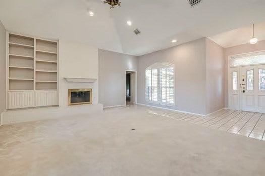 unfurnished living room with lofted ceiling and light carpet